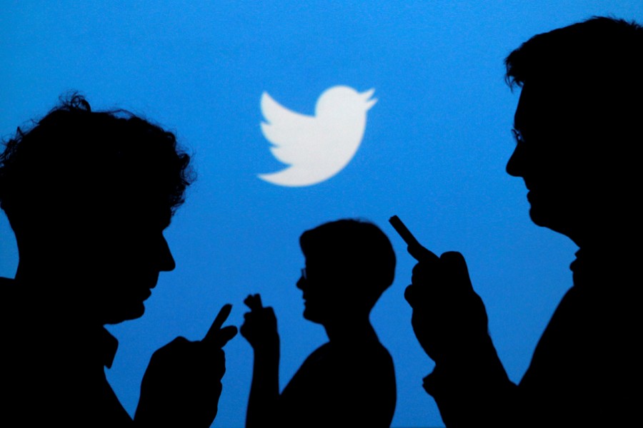 People holding mobile phones are silhouetted against a backdrop projected with the Twitter logo in this illustration picture taken on September 27, 2013 — Reuters/Files