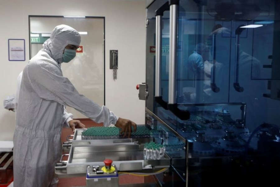 An employee in personal protective equipment (PPE) removes vials of AstraZeneca's COVISHIELD, coronavirus disease (Covid-19) vaccine from a visual inspection machine inside a lab at Serum Institute of India, in Pune, India on November 30, 2020 — Reuters/Files