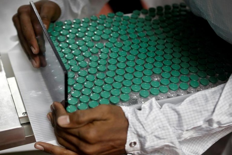 An employee in personal protective equipment (PPE) removes vials of AstraZeneca's COVISHIELD, coronavirus disease (Covid-19) vaccine from a visual inspection machine inside a lab at Serum Institute of India, in Pune on November 30, 2020 — Reuters/Files