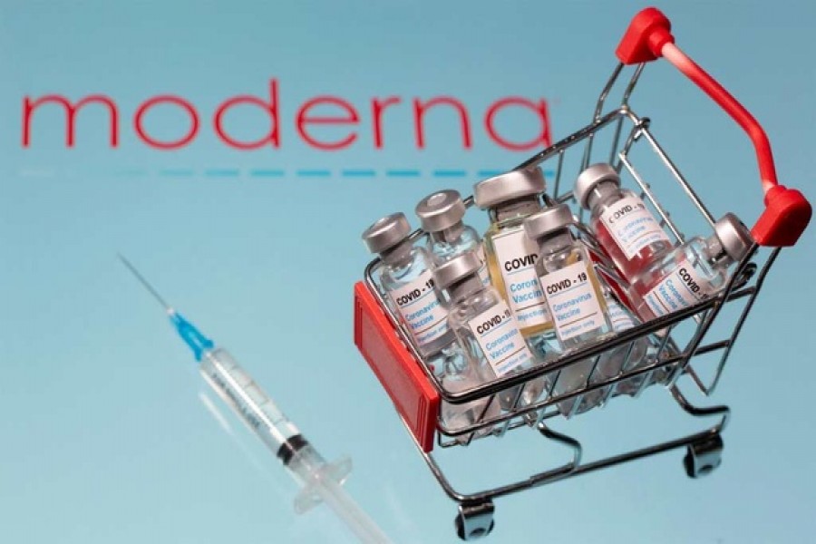 A small shopping basket filled with vials labelled "COVID-19 - Coronavirus Vaccine" and a medical sryinge are placed on a Moderna logo