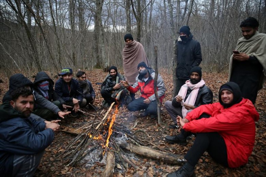 Migrants try to warm themselves near the burned migrant centre "Lipa" in Bihac, Bosnia and Herzegovina December 24, 2020. REUTERS/Dado Ruvic