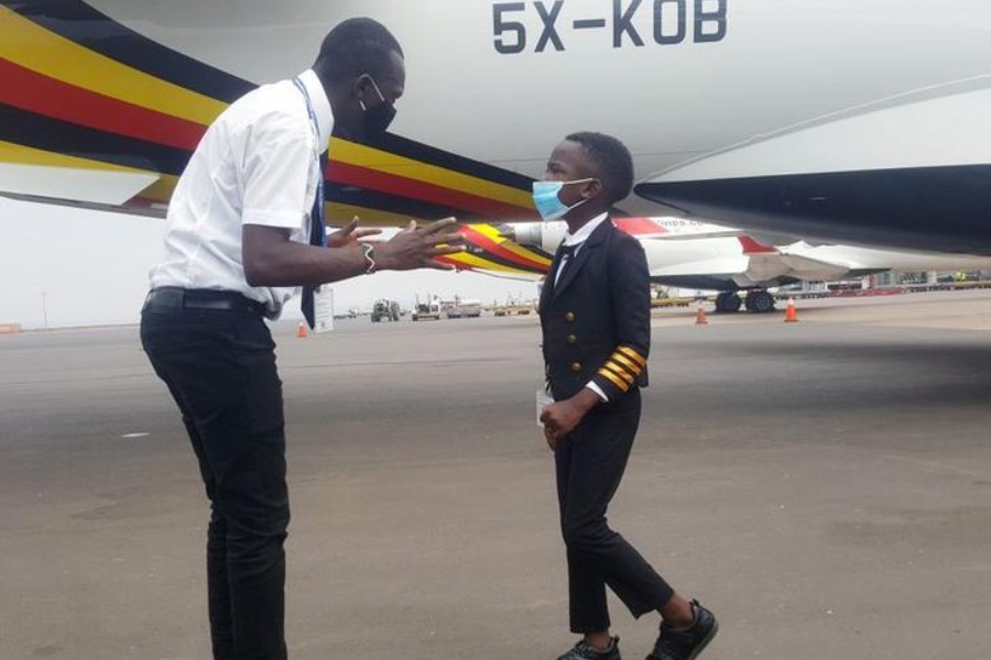 Ugandan "Captain" Graham Shema, 7, listens to his flight instructor, Simon Wadagu Bruno, about functions of some parts of a Bombardier CRJ900 aircraft at the Entebbe International Airport, in Entebbe, Uganda December 17, 2020. REUTERS/Elias Biryabarema