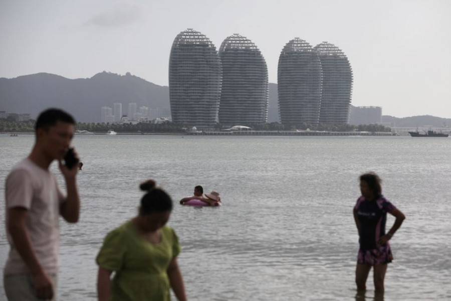 People are seen on Sanya Bay beach against the backdrop of Phoenix Island resort in Sanya, Hainan province, China November 26, 2020. REUTERS/Tingshu Wang/File Photo