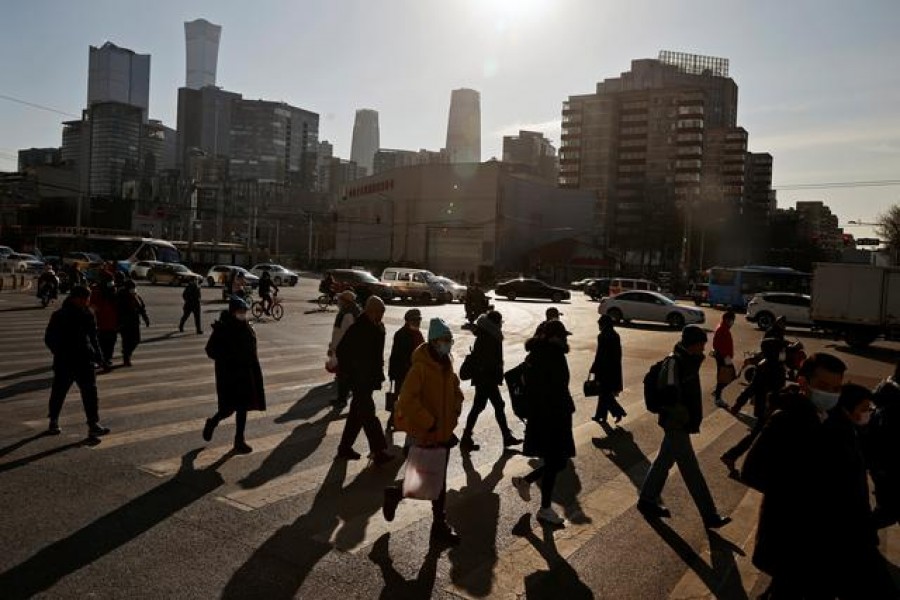 People cross a street during morning rush hour in front of the skyline of the central business district (CBD) in Beijing, China, December 15, 2020 — Reuters/Files