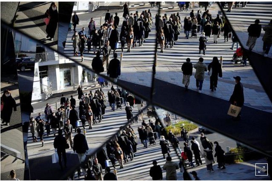 FILE PHOTO: Year-end shoppers wearing protective face masks are reflected on mirrors at a shopping and amusement district, amid the coronavirus disease (Covid-19) outbreak, in Tokyo, Japan December 31, 2020. REUTERS/Issei Kato/File Photo