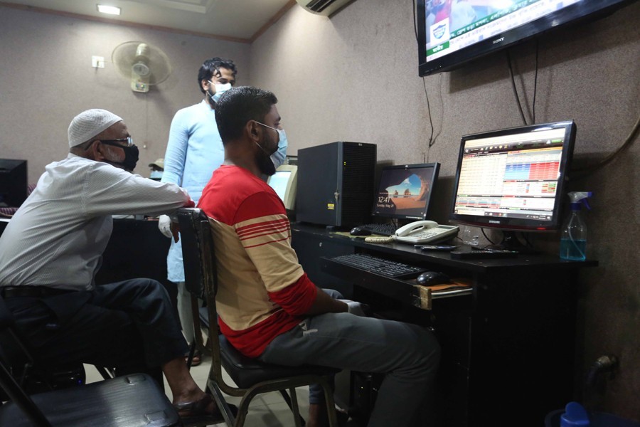 Traders, wearing masks, monitoring stock price movements on computer screens at a brokerage house in the capital city — FE/File