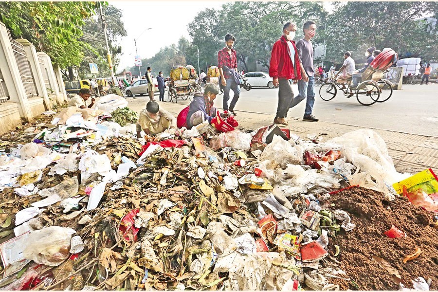 Pedestrians walk past a heap of garbage in the city’s Dhaka Medical College and Hospital area on Friday — FE photo