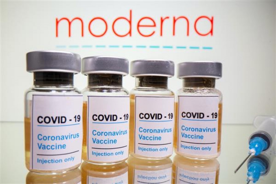 Vials with a sticker reading, "COVID-19 / Coronavirus vaccine / Injection only" and a medical syringe are seen in front of a displayed Moderna logo in this illustration taken on October 31, 2020