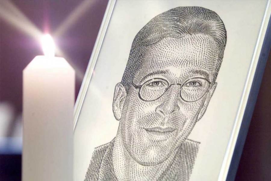 A portrait of the Wall Street Journal's reporter Daniel Pearl stands with a candle at the altar at Fleet Street's journalists chapel St Brides Church prior to a memorial service in London March 5, 2002. REUTERS/Ian Waldie IW/NMB