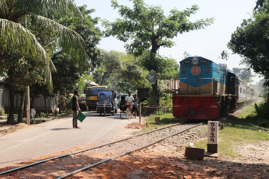 A student standing with green flag for giving signal at rail crossing at Vidyaganj Bazar, Chauhania in Mymensingh sadar — FE Photo