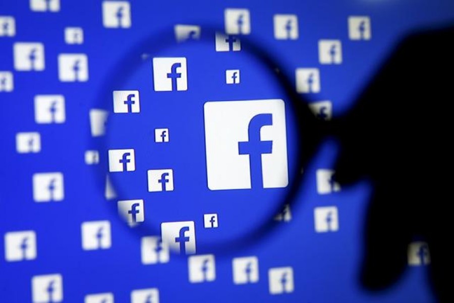 A man poses with a magnifier in front of a Facebook logo on display in this illustration taken in Sarajevo, Bosnia and Herzegovina on December 16, 2015