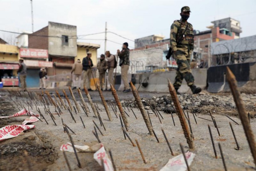 A security personnel walks past metal spikes on the ground installed by the Delhi police as a security measure at Tikri Border where farmers are protesting against farm laws, in New Delhi, India, February 4, 2021 — Reuters