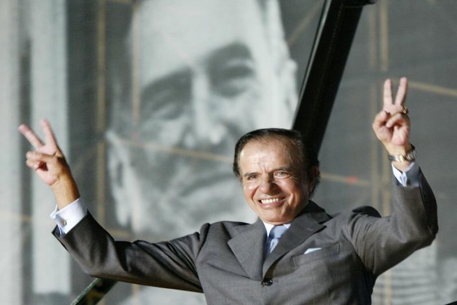 FILE PHOTO: Argentine presidential candidate Carlos Menem stands in front of a giant poster of former President Juan Domingo Peron, as he waves to thousands of followers in River Plate Stadium during the final rally of his campaign, in Buenos Aires, April 24, 2003. REUTERS/Rickey Rogers/File Photo