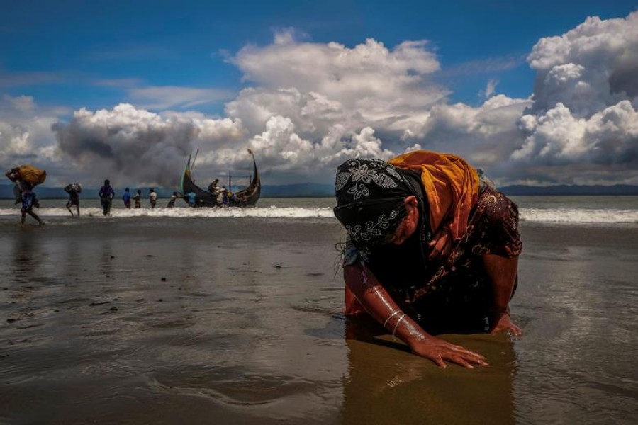 An exhausted Rohingya refugee woman touches the shore after crossing the Bangladesh-Myanmar border by boat through the Bay of Bengal, in Shah Porir Dwip, Bangladesh, September 11, 2017 — Reuters/Files