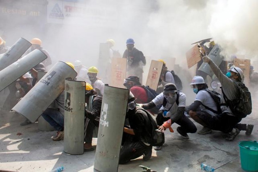 Protesters take cover as they clash with riot police officers during a protest against the military coup in Yangon, Myanmar, February 28, 2021 — Reuters/Stringer