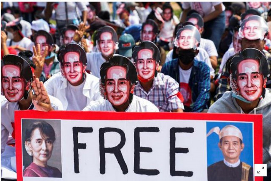 FILE PHOTO: Protesters wearing masks depicting ousted leader Aung San Suu Kyi, flash three-finger salutes as they take part in a protest against the military coup in Yangon, Myanmar, February 28, 2021. REUTERS/Stringer