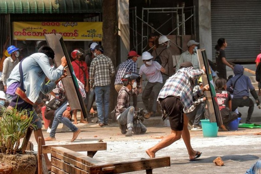 Protesters cover with makeshift shields during an anti-coup protest in Mandalay, Myanmar, March 3, 2021 — Reuters/Stringer