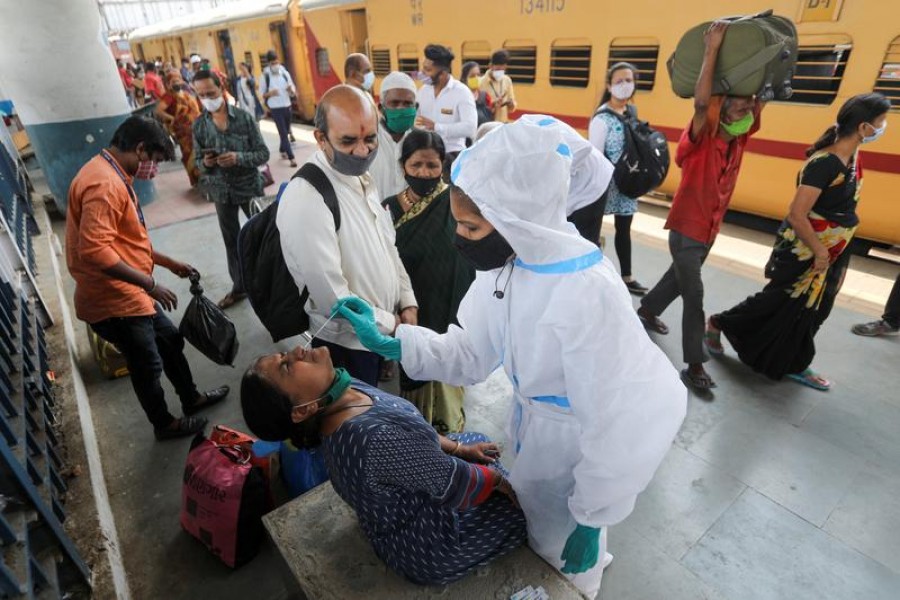 A health worker in personal protective equipment (PPE) collects a swab sample from a woman during a rapid antigen testing campaign for the coronavirus disease (COVID-19), at a railway station platform in Mumbai, India, March 17, 2021. REUTERS/Francis Mascarenhas