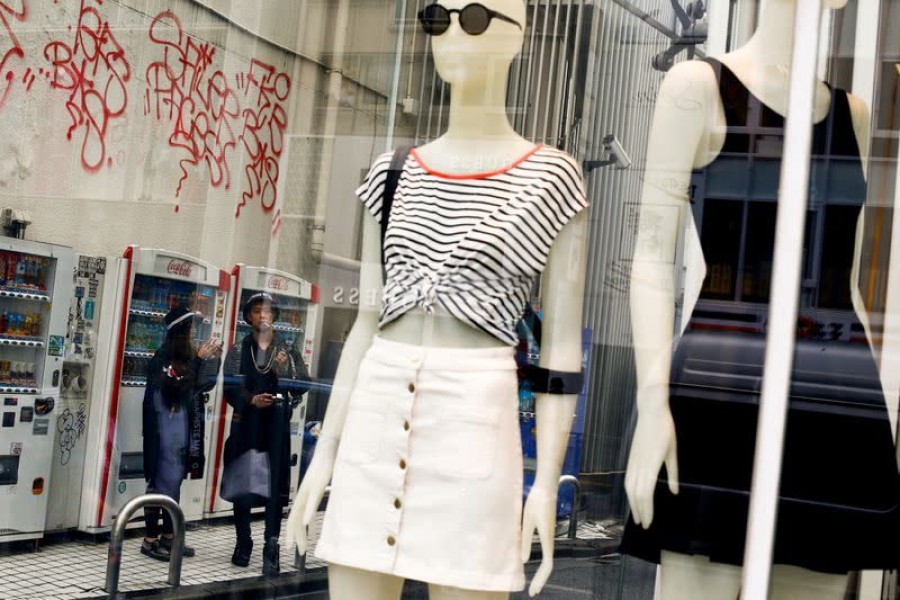 People stand next to the window of a fashion boutique in a shopping district in Tokyo, Japan, May 30, 2016 — Reuters/Files