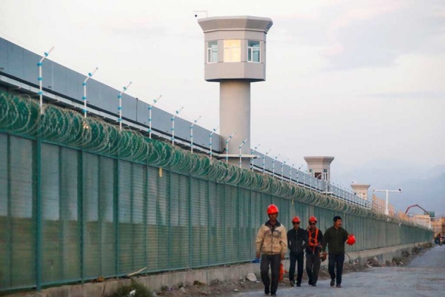 Workers walk by the perimeter fence of what is officially known as a vocational skills education centre in Dabancheng in Xinjiang Uighur Autonomous Region, China, September 4, 2018 — Reuters/Files