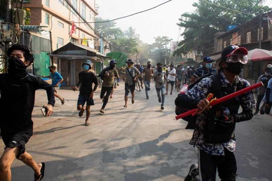 Men run during a protest against the military coup, in Yangon, Myanmar on March 28, 2021 — Reuters/Stringer