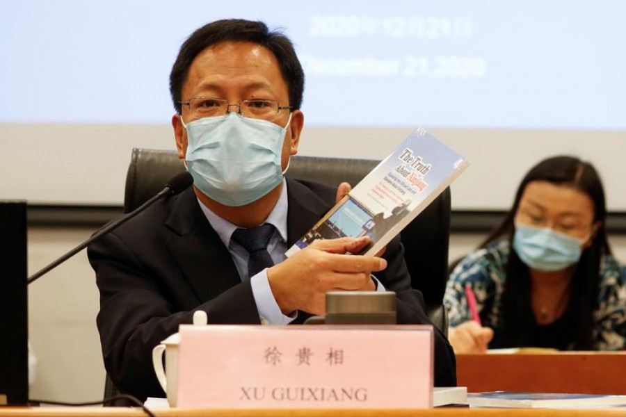 FILE PHOTO: Xu Guixiang, deputy head of Xinjiang's publicity department holds a copy of a booklet, as he speaks during a news conference in Beijing, China December 21, 2020. Picture taken December 21, 2020. REUTERS/Carlos Garcia Rawlins