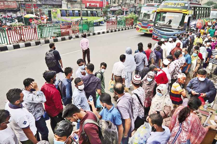 People waiting to board buses in Gulistan area of the city amid a lack of transport, as the bus operators, in line with the government directive to stem the spread of coronavirus, started plying vehicles from Wednesday with 50 per cent passengers against the capacity — FE photo by Shafiqul Alam