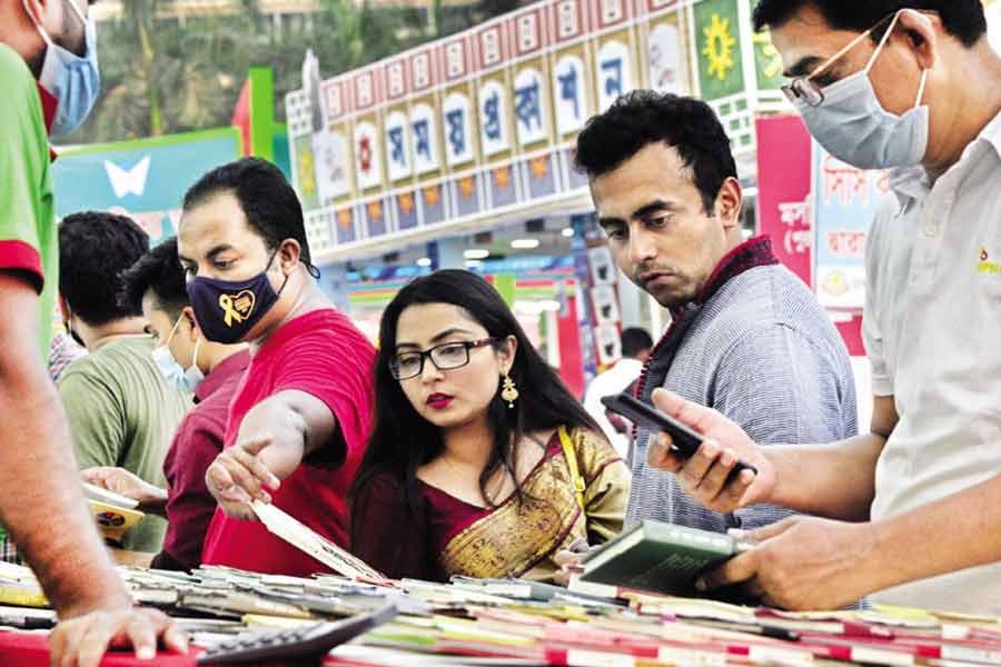 Without following health guidelines amid the surging pandemic, people flicking through books at a stall at the Amar Ekushey Book Fair at the Suhrawardy Udyan in the city on Friday —Focus Bangla Photo