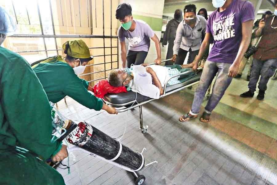 With the Oxygen mask on, a critical patient, who got admitted to the Mugda Medical College and Hospital in the city recently with respiratory symptoms, being hurriedly moved to the designated ward by his relatives and the hospital staff — FE file photo