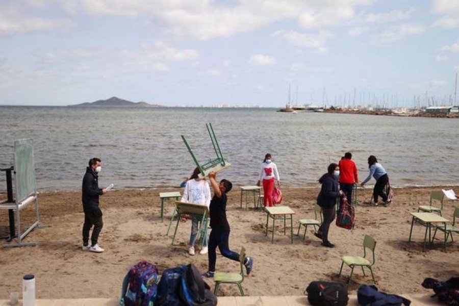 FILE PHOTO: Students and teachers of the Felix Rodriguez de la Fuente school remove chairs and tables at the end of their class, as part of a project known as 'Aire Limpio' (Fresh Air) at the Playa de los Nietos (The Grandchildren's Beach), which aims to use better air quality for children during the coronavirus disease (COVID-19) pandemic, near Cartagena, southern Spain April 8, 2021. REUTERS/Nacho Doce