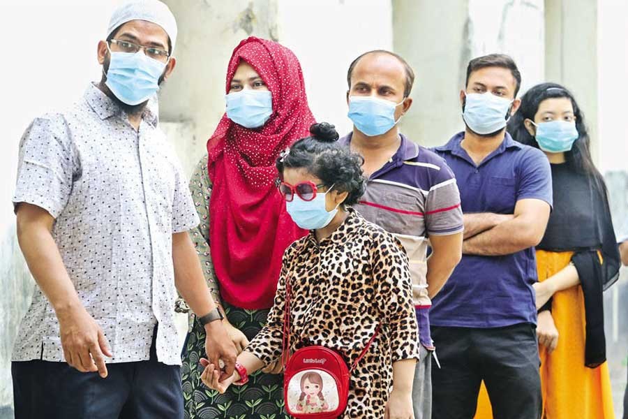 With the resurgence of coronavirus, more children are getting infected this time. The photo shows a little girl waiting in a queue at Bangabandhu Sheikh Mujib Medical University Hospital in the city on Tuesday to have her sample tested for the virus — FE photo by KAZ Sumon