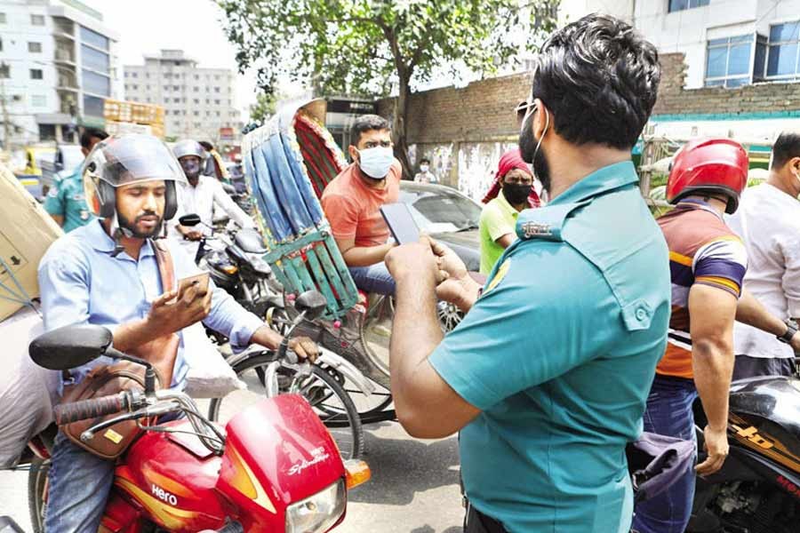 A policeman checks the movement pass on a mobile phone at Dayaganj in the city during lockdown on Thursday — FE photo