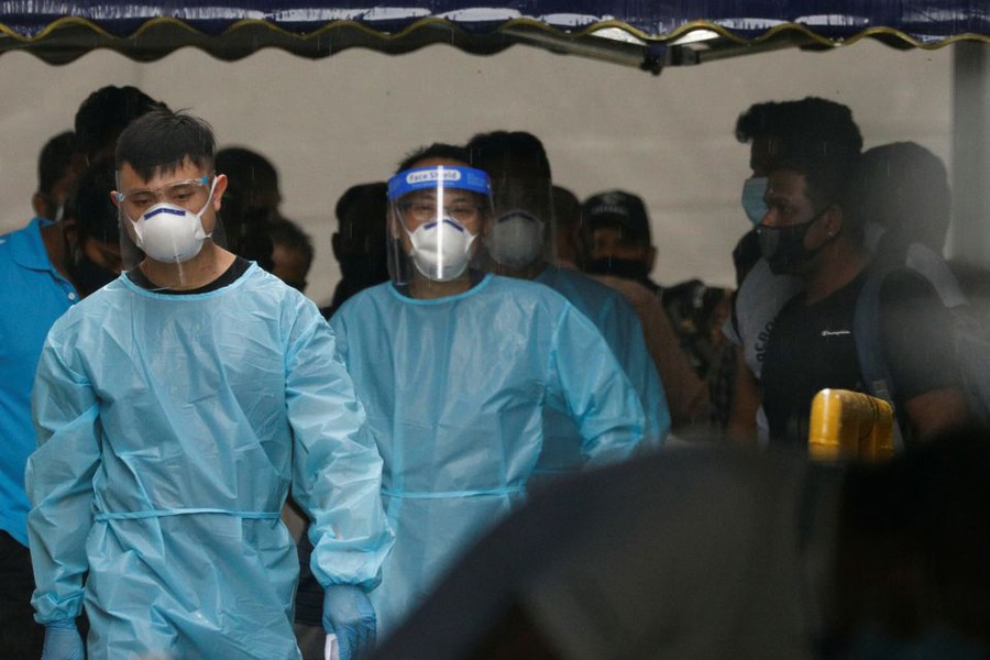 Personnel in protective garment usher a group of migrant workers to take a bus to a government quarantine facility after workers were tested positive for the coronavirus disease (Covid-19) at Westlite Woodlands dormitory in Singapore on April 22, 2021 — Reuters photo