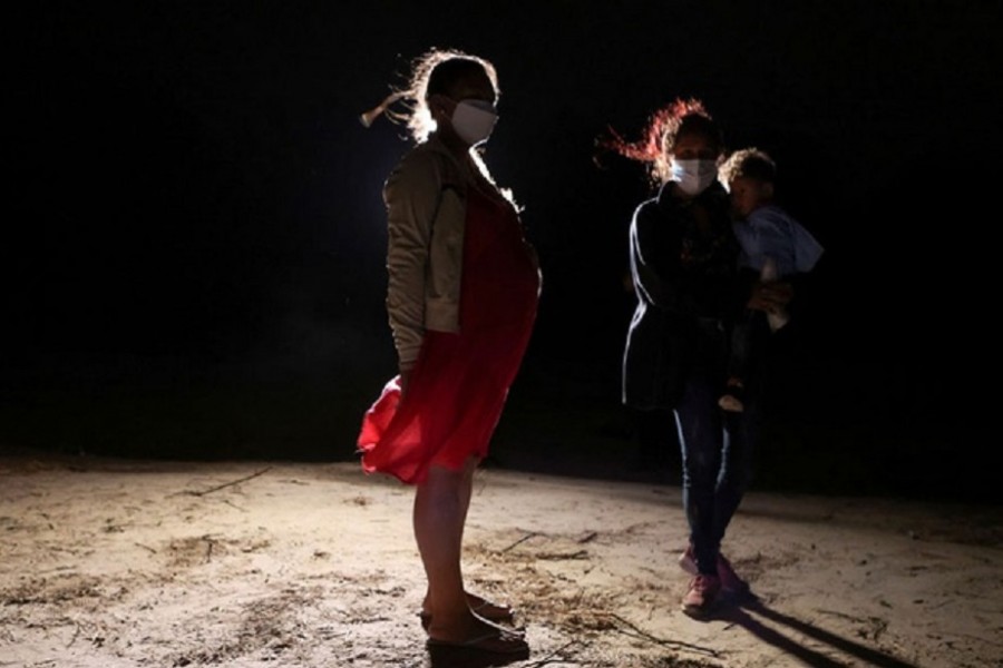 A pregnant asylum-seeking woman stands on the American side after crossing on an inflatable raft the Rio Grande river from Mexico, in Roma, Texas, US, April 22, 2021. Reuters