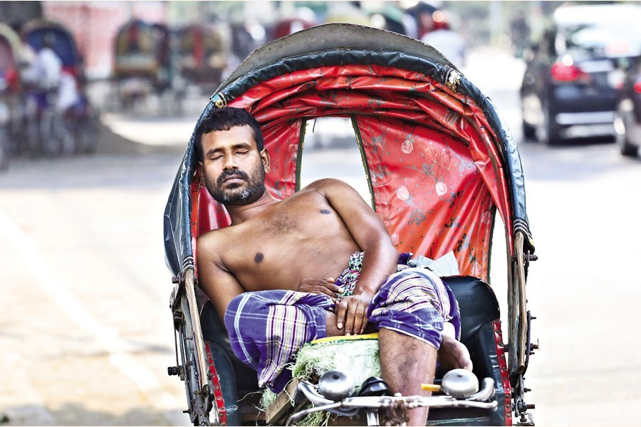 With a heatwave sweeping across the country, this rickshaw-puller taking a nap on his three-wheeler right under the shadow of a tree in the Palashi area of the city on Monday — FE photo by Shafiqul Alam