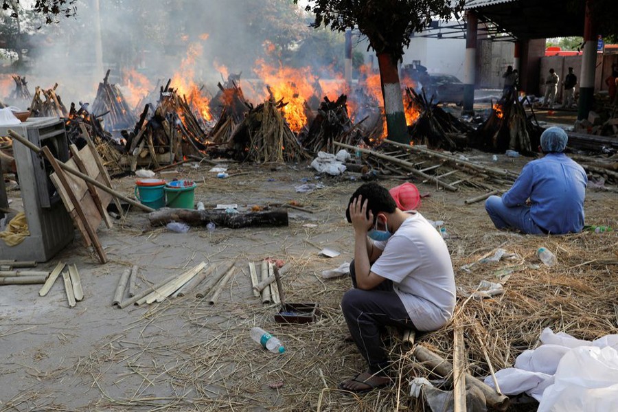 Family members sit next to the burning funeral pyres of those who died from the coronavirus disease (Covid-19), during a mass cremation, at a crematorium in New Delhi, India on April 26, 2021 — Reuters photo