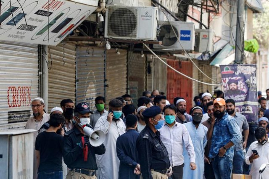 FILE PHOTO: A police officer uses megaphone to disperse shopkeepers, who gather to reopen their shops at a closed electronics market, as the lockdown continues during the efforts to stop the spread of the coronavirus disease (COVID-19), in Karachi, Pakistan April 27, 2020. REUTERS/Akhtar Soomro