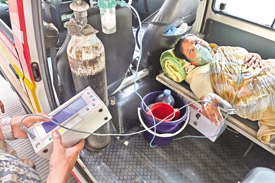 A health worker uses an oximeter to check the oxygen level of a patient on her arrival at Dhaka Medical College Hospital — FE file photo