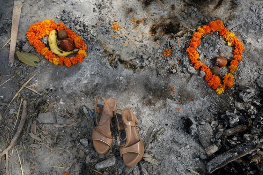 Flower garlands, fruits and a pair of sandals of a woman who died from the coronavirus disease (COVID-19), are placed by her relatives on the spot where she was cremated, as part of a ritual at a crematorium in New Delhi, India, April 30, 2021. Reuters