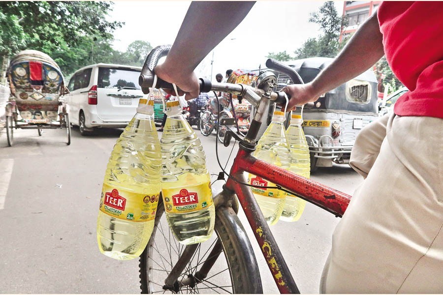 A man carries four bottles of soybean oil by his bicycle, as he makes his way home after buying the edible oil at a subsidised price from a sales point of TCB at Abdul Gani Road in the city on Tuesday — FE photo by Shafiqul Alam