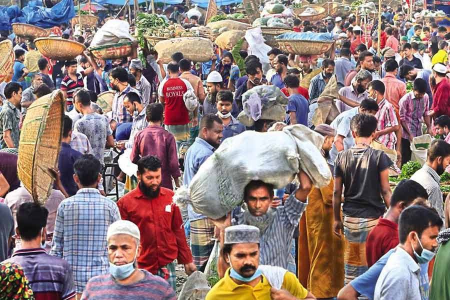 Sellers and buyers going about their business at Karwan Bazar kitchen market in the city on Tuesday, paying no heed to mask mandate or social distancing norms —FE photo by KAZ Sumon