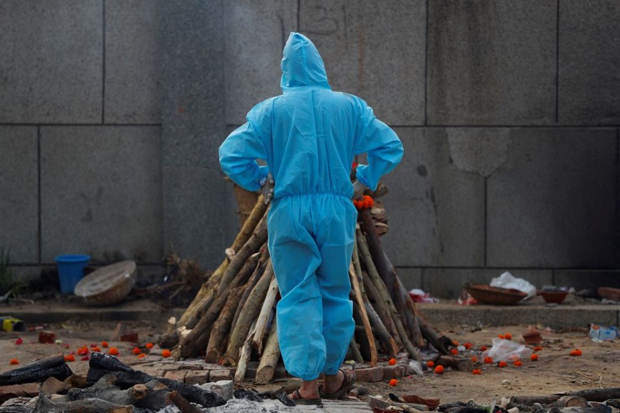 A man wearing personal protective equipment (PPE) stands next to a burning funeral pyre of a relative, who died from the coronavirus disease (Covid-19), before his cremation, at a crematorium in New Delhi, India on May 5, 2021 — Reuters photo