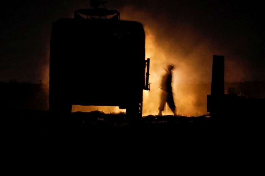 An Israeli soldier walks next to a military vehicle at a mobile artillery unit location on the Israeli side by the Israel border with Gaza May 16, 2021 - Reuters