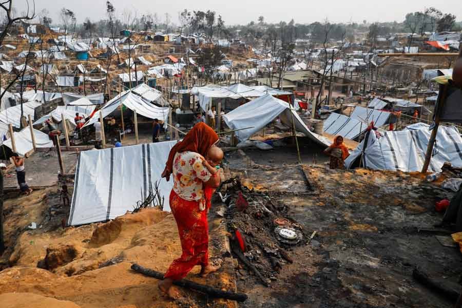 A Rohingya refugee woman carrying her child in Cox's Bazar on March 24 two days after a massive fire broke out in her camp –Reuters file photo