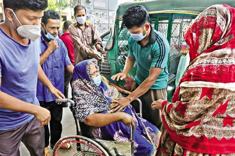 Relatives and a staffer of the Dhaka Medical College Hospital (DMCH) are taking Najufa Begum, who is in a wheelchair, inside the facility last month as she was having severe breathing problems —FE file photo