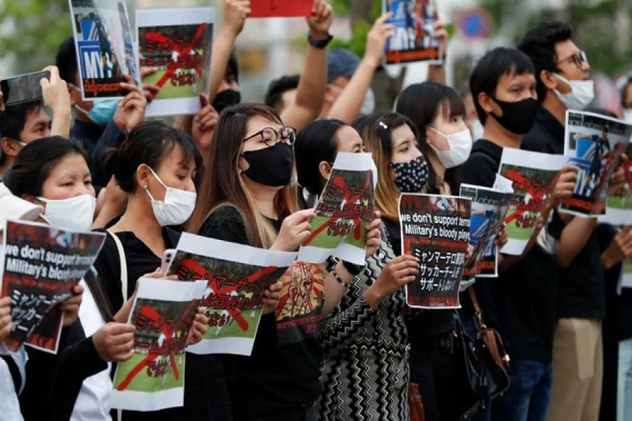 People hold placards during a rally of Myanmar protesters residing in Japan, outside the stadium before the FIFA World Cup Asia Qualifiers soccer match Japan v Myanmar at Fukuda Denshi Arena in Chiba, east of Tokyo, Japan May 28, 2021. REUTERS/Issei Kato