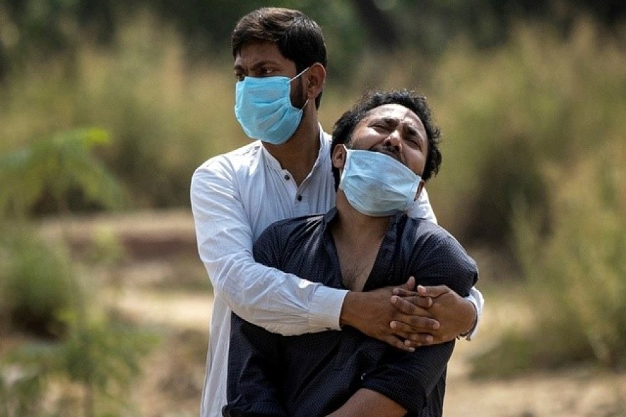 A man is consoled by his relative as he sees the body of his father, who died from complications related to the coronavirus disease (Covid-19), before his burial at a graveyard in New Delhi, India, April 16, 2021 — Reuters/Files