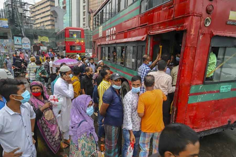 People defy physical distancing rules as they scramble to get on a bus to return home after a long wait at Karwan Bazar in Dhaka with rains worsening a transport crisis on Sunday. –bdnews24.com photo