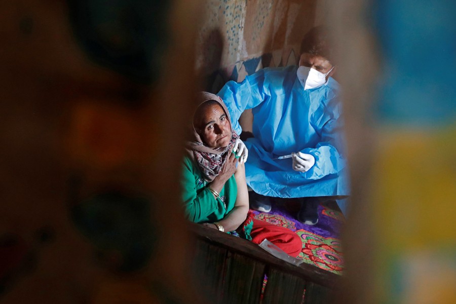 A shepherd woman is reflected as she receives a dose of COVISHIELD, a coronavirus disease (Covid-19) vaccine manufactured by Serum Institute of India, inside her hut during a vaccination drive at a forest area in south Kashmir's Pulwama district on June 7, 2021 — Reuters photo