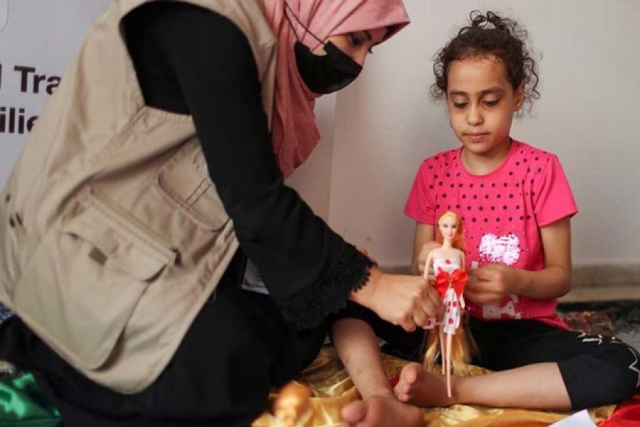 A psychologist plays with Palestinian girl Suzy Eshkuntana, who was pulled out from the rubble of her house, destroyed by an Israeli air strike during Israeli-Palestinian fighting, as part of a mental health support session in Gaza City, June 3, 2021. REUTERS/Mohammed Salem